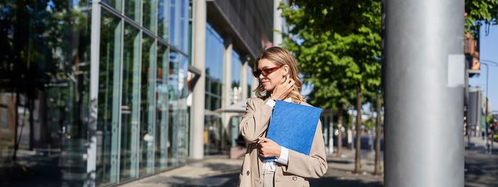 Portrait of young woman standing in city