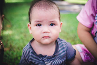 Close-up portrait of cute baby boy on field
