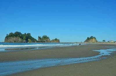 Scenic view of beach against clear blue sky
