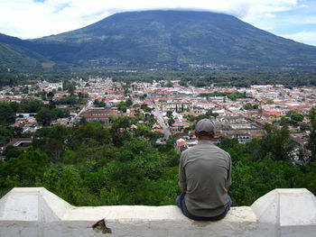 Rear view of man looking at town in mountains