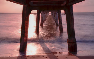 Pier on sea against sky during sunset