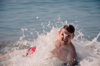 Portrait of cheerful young man diving in water at beach