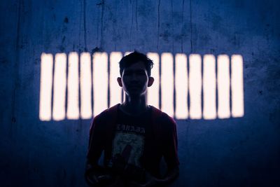 Full length of man standing against illuminated wall