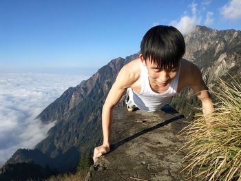 Full length of man doing push-ups on mountain against sky