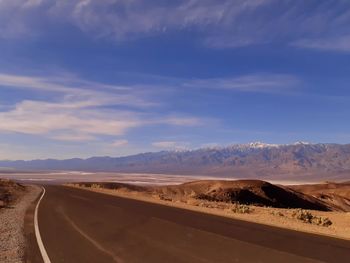 Road by desert against sky