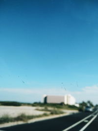 Road seen through car window against clear blue sky