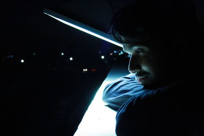 Portrait of young man looking away at night