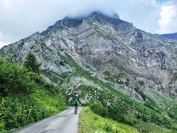 Rear view of person on mountain road against sky