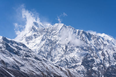 Scenic view of snowcapped mountains against blue sky