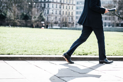 Low section of man with umbrella on city in background