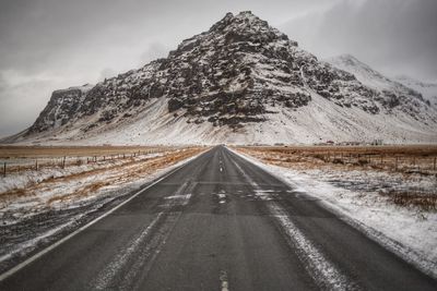 Road amidst snowcapped mountains against sky