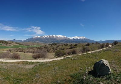 Scenic view of landscape and mountains against blue sky