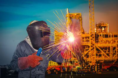 Man working on metal structure against sky