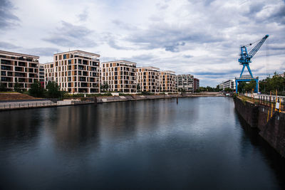 Bridge over river by buildings against sky