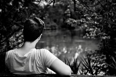 Rear view of woman sitting by lake