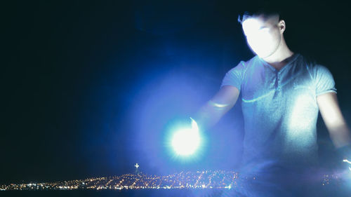 Midsection of man with illuminated lighting equipment at night