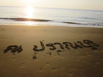 Text on sand at beach against sky