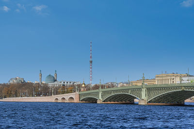 Arch bridge over river against clear blue sky