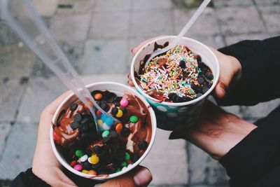 High angle view of cropped hands holding ice cream outdoors