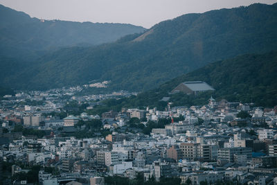 Aerial view of townscape and mountains against sky