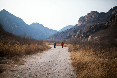 People walking on road against mountain range