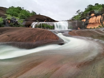 Scenic view of waterfall against sky