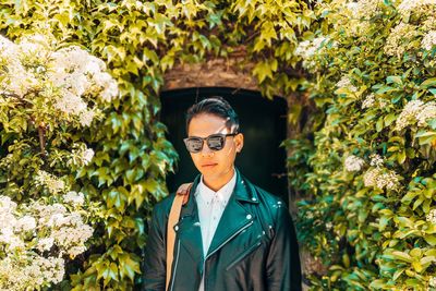 Portrait of man wearing sunglasses while standing against plants