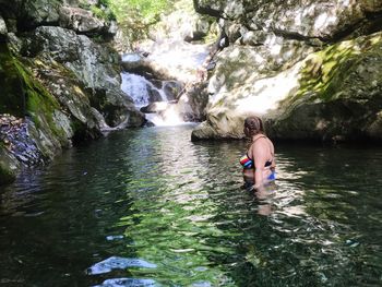 Man surfing on rock in river