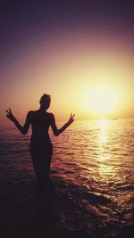 Silhouette of woman in sea at sunset