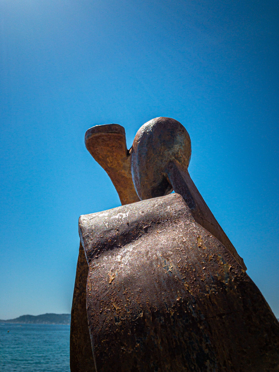 LOW ANGLE VIEW OF RUSTY STATUE AGAINST BLUE SKY