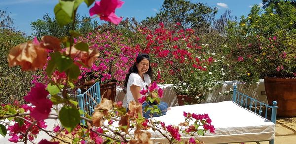 Portrait of woman by flowering plants against trees