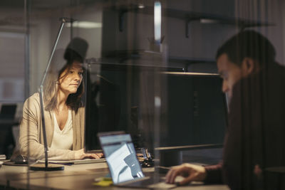 Woman using laptop while sitting on table