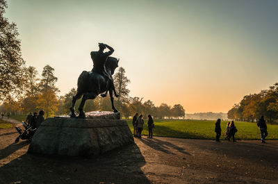 Statue on field against clear sky during sunset