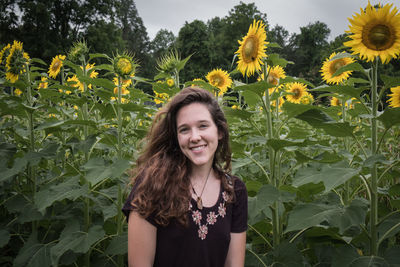 Portrait of smiling beautiful woman against sunflowers at field