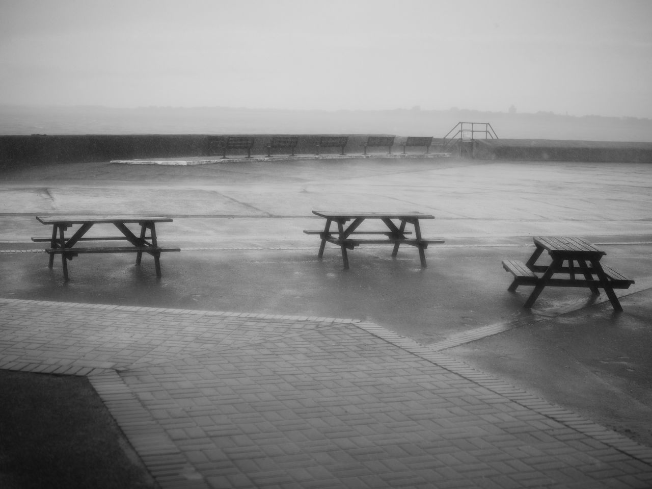 EMPTY BENCH ON TABLE BY ROAD DURING RAINY SEASON