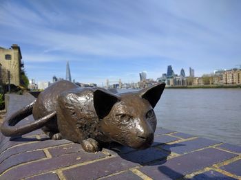 Close-up of statue by cityscape against sky