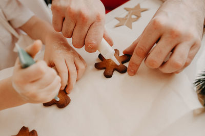 Hands of mom and baby painted on christmas cookies with food coloring on baking paper