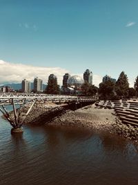 Buildings by river against sky in city