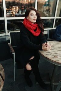 Beautiful woman wearing scarf sitting at table outside cafe