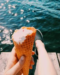 Close-up of hand holding ice cream against lake