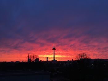 Silhouette of communications tower against sky at sunset
