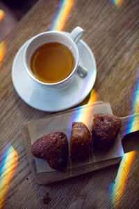 On the wooden table is a cup of tea and cookies heart