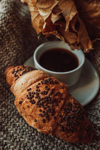 A cup of black morning coffee with a chocolate croissant. delicious meal. aesthetics in details