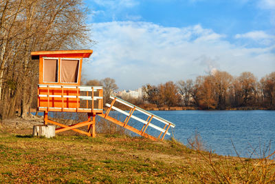 Autumn landscape of a deserted river bank with a wooden lifeguard tower in the golden rays. 