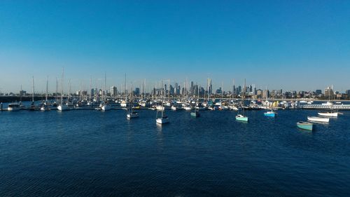 Boats in sea against clear blue sky