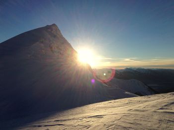 Sun shining through clouds over mountain