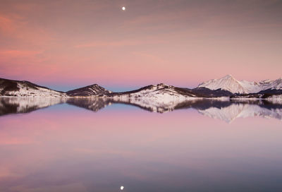 Scenic view of lake and mountains against sky during sunset