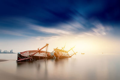 Fishing boat in sea against sky at sunset
