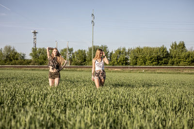 Friends standing on grassy field against sky