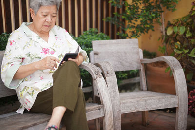 Portrait of young woman using mobile phone while sitting on bench